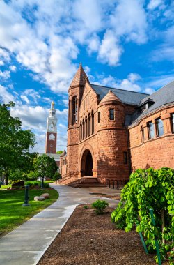 Romanesque Revival mimarisi ile kırmızı kumtaşından yapılmış tarihi Billings Kütüphanesi, Burlington 'daki Vermont Üniversitesi kampüsündeki Ira Allen Şapeli' nin beyaz saat kulesinin yanında duruyor.