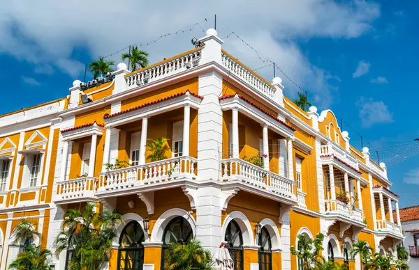 Kolombiya, Cartagena 'nın tarihi bölgesinde parlak mavi gökyüzü ve tropikal güneş ışığı altında parıldayan parlak turuncu cephesi beyaz sütunları ve balkonları olan canlı bir koloni binası bulunmaktadır.