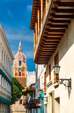 Kolombiya 'daki Cartagena Katedrali, mavi gökyüzünün altında geleneksel ahşap balkonlar ve klasik fenerler tarafından çerçevelenmiş dar bir sömürge caddesinin üzerinde yükseliyor.