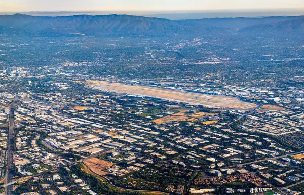 Kaliforniya 'daki San Jose Mineta Uluslararası Havalimanı' nın havalimanı, pistlerinin endüstriyel binalar, yerleşim alanları ve açık sabah ışığı altında Santa Clara Vadisi etekleriyle çevrili olduğunu gösteriyor.