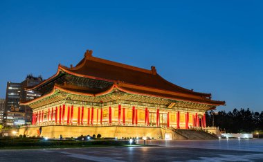 Tayvan 'ın Taipei kentindeki Ulusal Tiyatro, akşam ışıkları altında parıldıyor, parlak kırmızı sütunları ve süslü çatısı Özgürlük Meydanı' ndaki derin mavi gökyüzüne karşı duruyor.