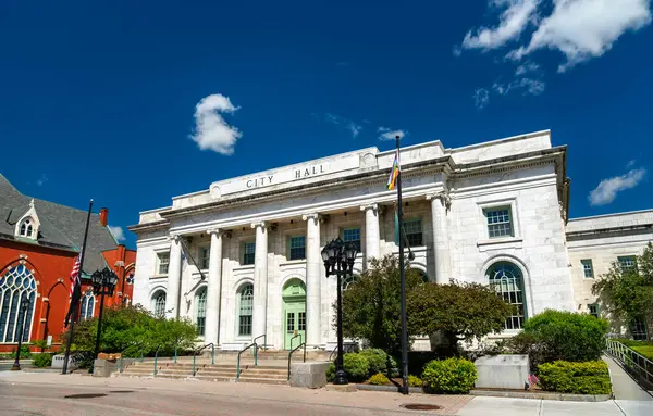 Pittsfield Massachusetts 'teki Neoklasik Beyaz Taş Belediye Binası' nda sakin bir meydan boyunca uzun sütunlar ve kemerli pencereler bulunmaktadır. Temiz gökyüzü ve güneş ışığı, yan taraftaki tarihi hükümet yapısının mimari detaylarını vurguluyor.
