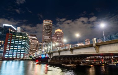 Boston, ABD, Evelyn Moakley Köprüsü Fort Point Kanalı boyunca uzanır şehir merkezindeki gökdelenler sakin liman suyuna renkli gece yansımaları yapar..