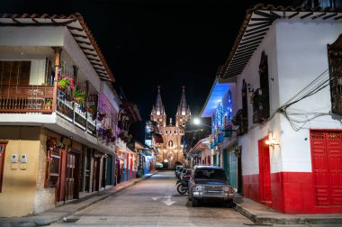 Colombiya 'nın Jardin şehrinde gece vakti, Lekesiz Gebelik Bazilikası' na giden yol renkli koloni binalarıyla doludur.