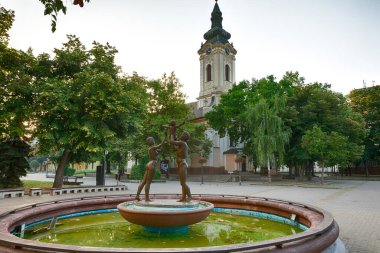 Arka planda kilise olan Şehir Çeşmesi - Kikinda, Sırbistan