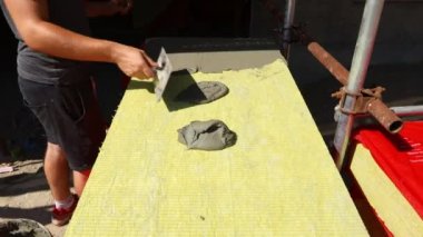 İşçinin eline malayla bak, yalıtım için sarı mineral yününe yapıştırıcı sür bina, inşaat alanı.... 