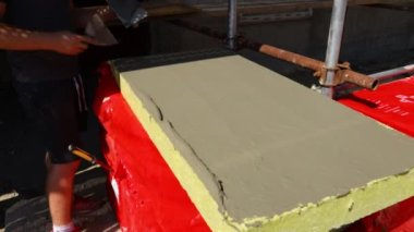 İşçinin eline malayla bak, yalıtım için sarı mineral yününe yapıştırıcı sür bina, inşaat alanı.... 