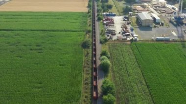 Hava manzarası, insansız hava aracı geri gidiyor, uzun kompozisyonun üzerinden uçuyor, boş yük treni, ekili arazileri geçiyor. Olgun buğday, mısır, yeşil bitki örtüsünde ayçiçeği, bölünmüş tarım alanları.