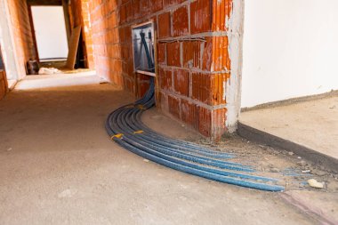 Yeni dağıtım sistemi yapım aşamasındaki bir binanın merkezi ısıtma katı için monte edildi. Beton zeminden geçen mavi boru hatları yığını.