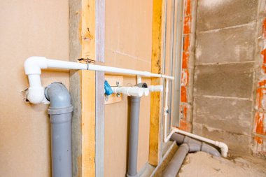 Yeni su tesisatı, plasterboard duvarına monte edilmiş gri PVC lağım boruları..