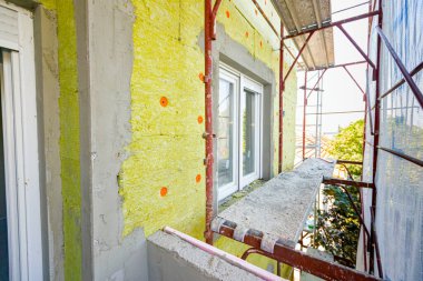 Applied thermal isolation stone wool on the brick wall of residential building under construction, heat isolation with mineral wool.