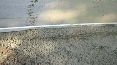 İnşaat işçisi eldiven takıyor. Döküldükten sonra betonu metal katmanla dümdüz ediyor.. 