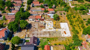Aerial view on construction site in cityscape, mixer truck pouring concrete into pump machine pumping to exit tube, worker is directing the on right direction, building foundation. 
