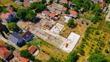 Aerial view on construction site in cityscape, mixer truck pouring concrete into pump machine pumping to exit tube, worker is directing the on right direction, building foundation. 