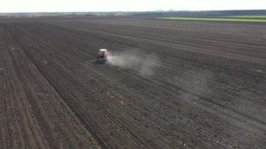Üst görünümde, doli attıkça traktör üzerinde ilerler, yeni ekinler için tarıma elverişli tarım arazileri, yapay gübre yaymak için monte edilmiş tarım makineleri sürükler..