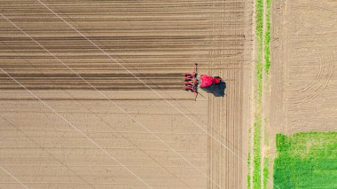 Üstten bakıldığında, traktörün tarla, toprak, yeni tahıl, mısır, mısır ekimi üzerine mekanik tohum ekme makinesi çekmesi..