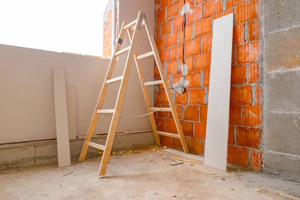 建設現場で画家の木製のはしごを折り モンタージュの準備ができて石膏ボードは インストールされているインストールと赤レンガの壁にもたれています 建物の建設中 — ストック写真