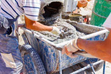 Ekip çalışması, işçiler havan topu karıştırma makinesinden el arabasına taze havan topu döküyorlar. İnşaat alanı çalışıyor