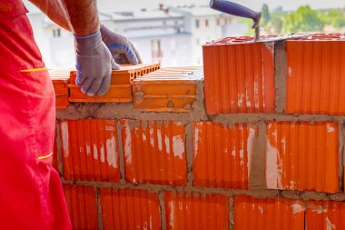 Mason, tuğla ustası düz olması için tel hattının yanına duvar örüyor..