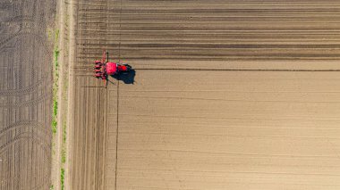 Üstten bakıldığında, traktörün tarla, toprak, yeni tahıl, mısır, mısır ekimi üzerine mekanik tohum ekme makinesi çekmesi..