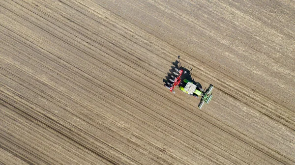위에서 트랙터 경작지 기계를 당겨서 새로운 곡물식 옥수수 옥수수를 수있다 — 스톡 사진