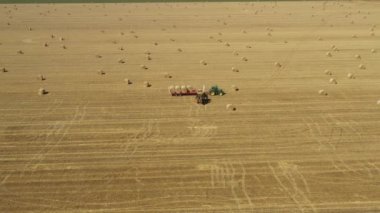 Kazıcının üstünde, karavana saman balyaları yüklerken, tarla arazisinde traktörle çekilirken, forklift bıçağı ve ek taşıyıcı kullanarak,.