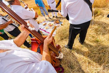 Kontrabasist, müzisyen ahşap, jingle bells çubuk müzik perküsyonu kullanarak kontrabass çalıyor. Çiftçilerin geleneksel kırsal alanda tahıl toplamaya başlamalarından önce mutluluk ve başarı müziği.