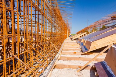 Kiriş, köprü iskeleti, takviye, dikey çapraz paslı armatür çubuklar ve inşaat alanına boyanmış ahşap kalıplar.. 