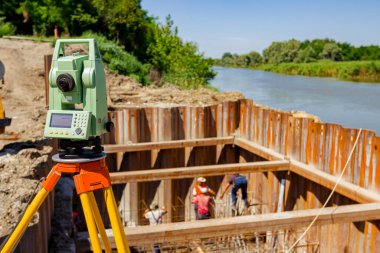 İnşaat alanındaki elektronik dengeleyici büyük inşaat projelerine girişmeden önce hassas ölçümler yapılmasını sağlıyor. Nehir kıyısı boyunca köprü temeli için metal yığınları