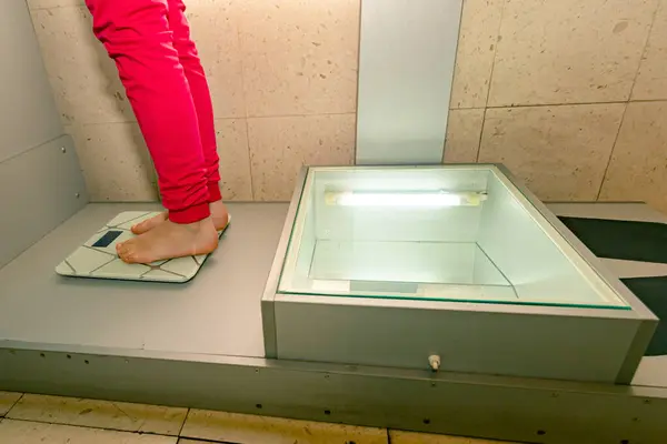 Child\'s foot is standing on modern floor scale measuring her weight.