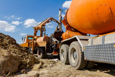 Karıştırıcı kamyonu inşaat alanında sevkiyat yapıyor. Pompa makinesiyle kamyondan kamyona taze beton dökülüyor..
