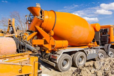 Karıştırıcı kamyonu inşaat alanında sevkiyat yapıyor. Pompa makinesiyle kamyondan kamyona taze beton dökülüyor..