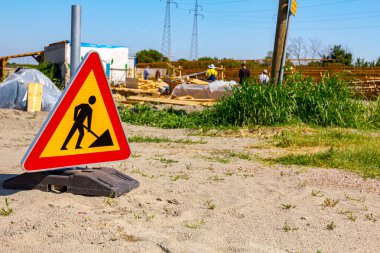 Uyarı sembolü olan üçgen trafik levhası inşaat alanının önüne yerleştirildi..