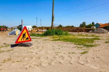 Uyarı sembolü olan üçgen trafik levhası inşaat alanının önüne yerleştirildi..