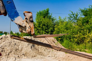 Teslimat ve ulaşım için forklift makineleri, yerden seçilen uzun paslı armatür çubuklarını inşaat alanından kaldırıyor.