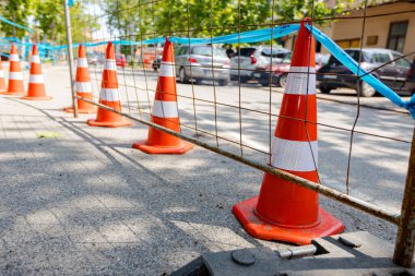 Şehir yolunun yanındaki inşaat alanının önüne aktif trafiği olan bir barikat kuruldu. Plastik ayaklı mobil metal çitler geçici tel panellerin dengesi içindir..