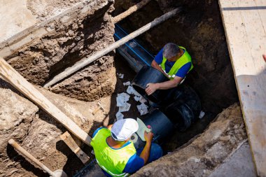 Yeni plastik bir HDPE boru hattı kuran işçiler, yeraltı su şebekesinin dirseği.