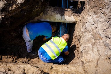 Yeni plastik bir HDPE boru hattı kuran işçiler, yeraltı su şebekesinin dirseği.