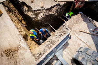Yeni plastik bir HDPE boru hattı kuran işçiler, yeraltı su şebekesinin dirseği.