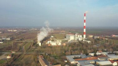 Yukarıda, doli yörüngede hareket ediyor, bacası ve soğutma kuleleri olan termik enerji santrali. Bölgesel ısınma ve çevre kirliliği üretiminde bacadan beyaz duman çıkıyor.