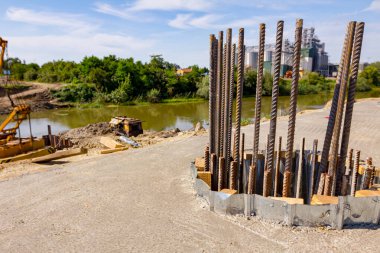 Üst kısım, armatür parmaklıklar, üsteki beton sütundan takviye. Mobil vinç, arkaplanda metal yığınları olan köprü temeli