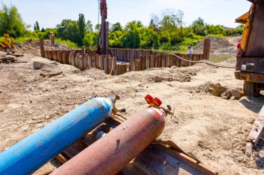 Kırmızı ve mavi kaynak ekipmanları, oksijen ve nitrojen tankları valfler ve basınç göstergeleri, inşaat alanındaki metal kazıklara asetilen gaz silindirleri yerleştirildi.