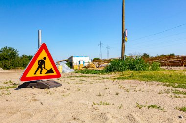 Uyarı sembolü olan üçgen trafik levhası inşaat alanının önüne yerleştirildi..