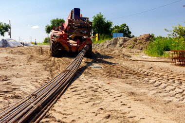 Teslimat ve ulaşım için forklift makineleri, yerden seçilen uzun paslı armatür çubuklarını inşaat alanından kaldırıyor.