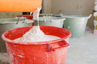 Beyaz macun, alçı ve suyu birkaç büyük kovada karıştırmak için elektrikli mikser..