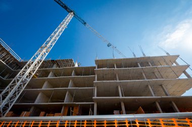 Turuncu, plastik, güvenlik ağı ile sınırlı alan tamamlanmamış çok katlı bir binanın etrafına yerleştirildi..