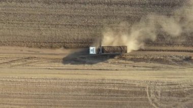 Üst manzarada, dolly yukarı doğru hareket ediyor, taze toplanmış şeker pancarı kökleri ile dolu nakliye kamyonunu takip ediyor kirli yolda ilerliyor, ekili tarlalar arasında çok toz yapıyor.