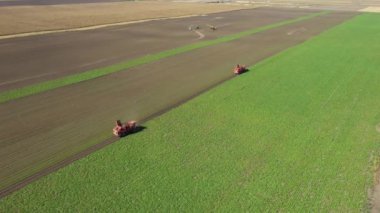 Dolly 'nin üzerinde iki tarım makinesinin, hasatçıların, tarım alanında olgun şeker pancarı köklerini kesip biçerek, ekip çalışması yaptığı görülüyor..
