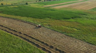 Tırmıkla bağlı traktör dönüyor ve kuru otları topluyor saman demetleri ya da balyalar için uzun kuyruklar oluşturuyor. Tarım makineleri, çayırda kurumuş mahsulü döndürmek için parmak tırmığı.
