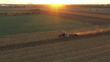 Dolly 'nin traktörü çekiş makinesi olarak kullanması, disk kirişi kırıcı, toprağı bir sonraki hasat için hazırlıyor. Kuş sürüsü yiyecek aramak için tarımsal makineyi takip ediyor. Gün batımı ve arka plan